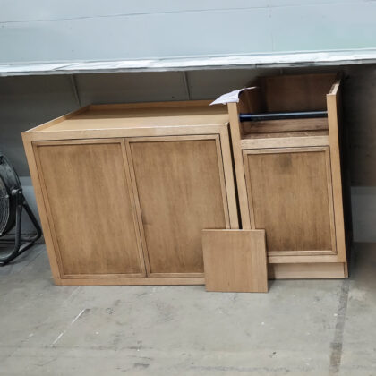 Brown stained wall cabinet and base cabinet with paper towel holder accessory in a warehouse.