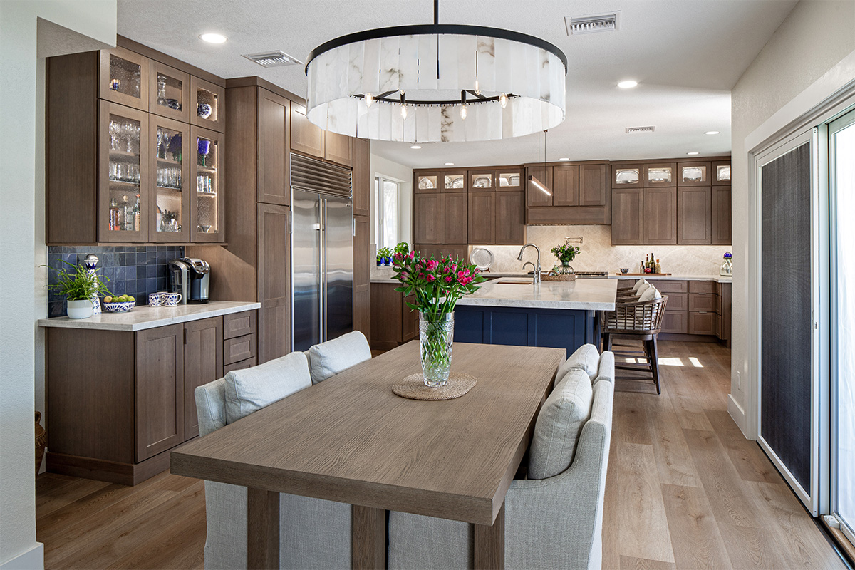 Brown-stained kitchen cabinets and dining table with a blue pained island.