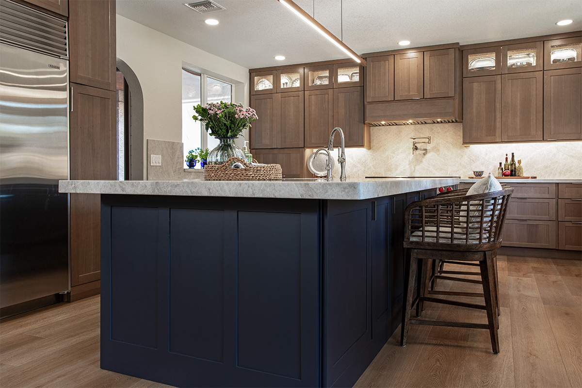 Brown-stained kitchen cabinets with a blue pained island.