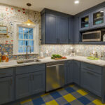 Blue kitchen cabinets with blue and yellow checkered floor and colorful backsplash.