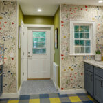 Blue kitchen cabinets with blue and yellow checkered floor and colorful backsplash.