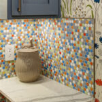 Blue kitchen cabinets with blue and yellow checkered floor and colorful backsplash.