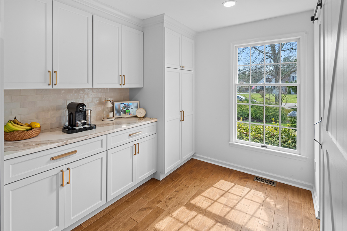 White kitchen cabinets near a large window