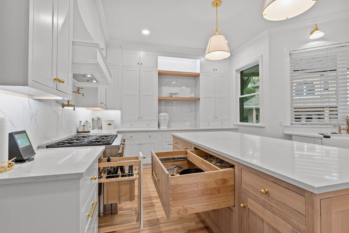White kitchen perimeter cabinets with an island in washed out light brown Vita stain on Rift White Oak. Shows drawers open displaying organization accessories installed.