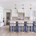 Kitchen with white perimeter and blue island cabinets.