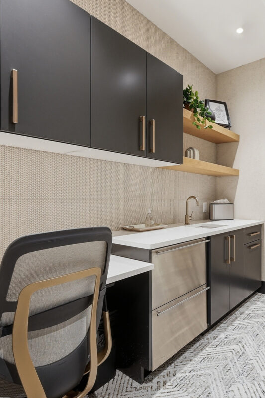 Gray painted office cabinets and desk with small kitchenette.