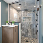 Brown stained bathroom vanity next to a glass steam shower.