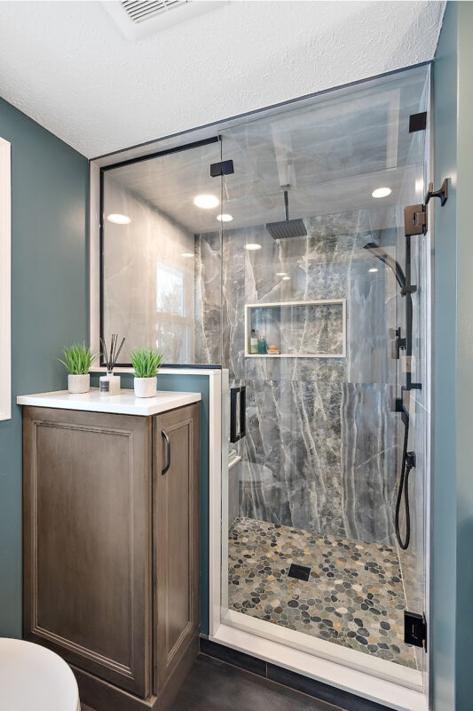Brown stained bathroom vanity next to a glass steam shower.