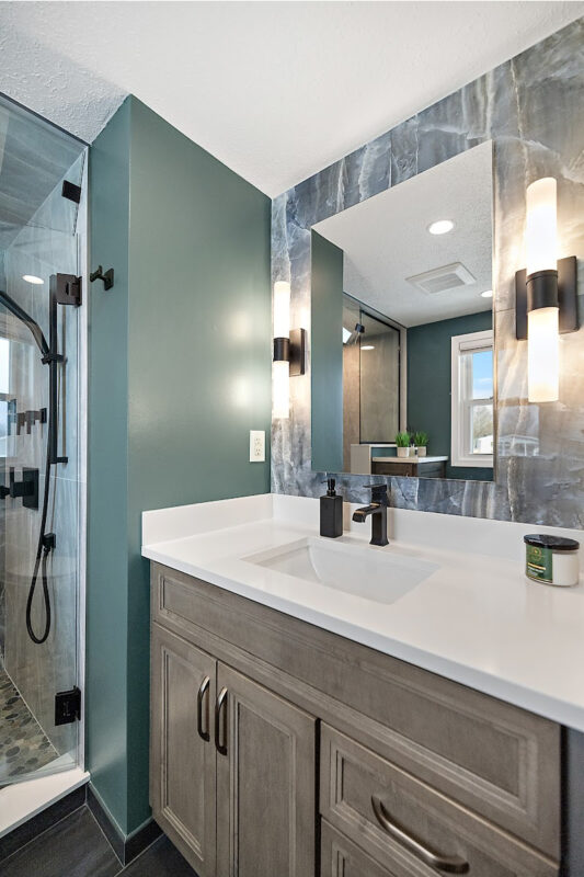 Brown stained bathroom vanity next to a glass steam shower.