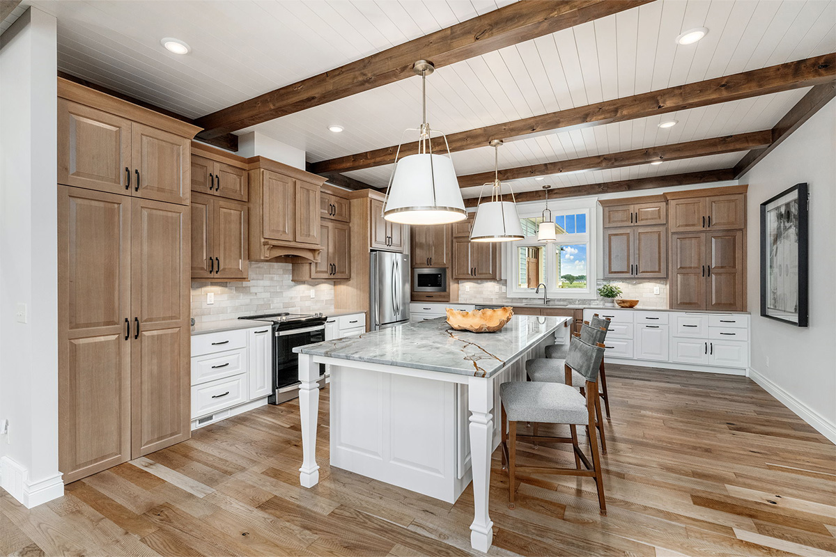Brown-stained and white kitchen perimeter and island cabinets. Island includes decorative legs and seating.
