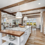 Brown-stained and white kitchen perimeter and island cabinets. Island includes decorative legs and seating.
