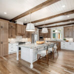 Brown-stained and white kitchen perimeter and island cabinets. Island includes decorative legs and seating.