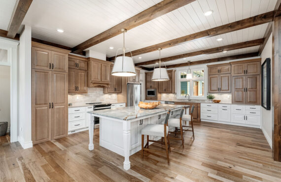 Brown-stained and white kitchen perimeter and island cabinets. Island includes decorative legs and seating.