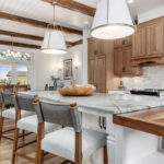 Brown-stained and white kitchen perimeter and island cabinets. Island includes decorative legs and seating.
