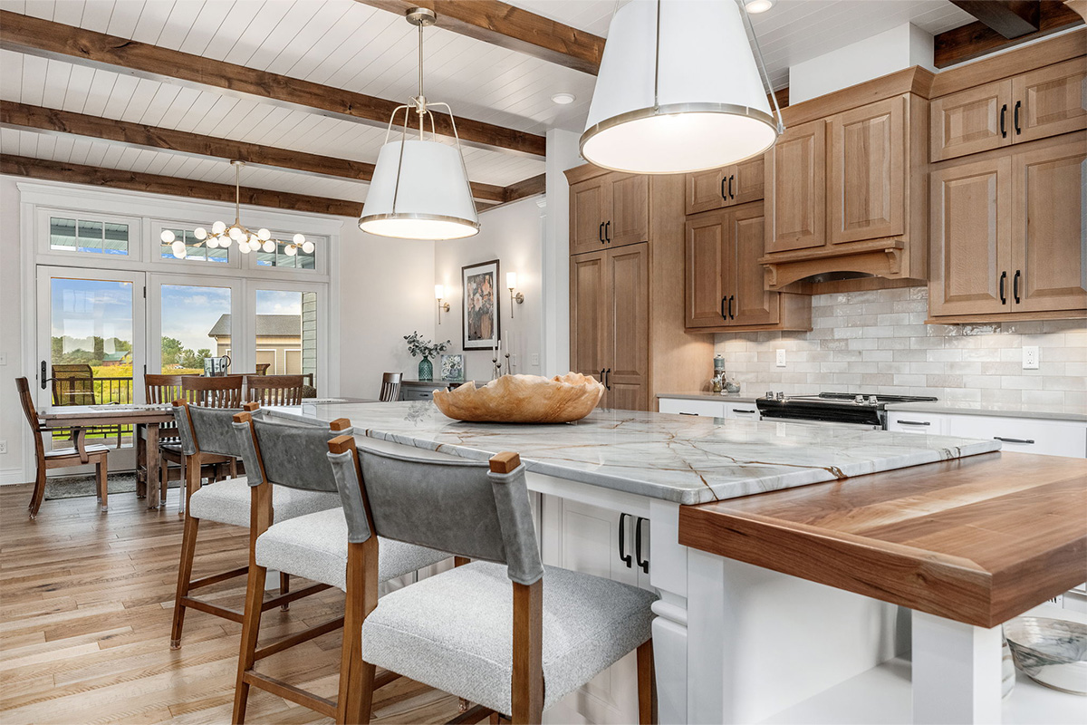 Brown-stained and white kitchen perimeter and island cabinets. Island includes decorative legs and seating.