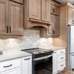 Brown-stained and white kitchen cabinets with black oven.