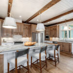 Brown-stained and white kitchen perimeter and island cabinets. Island includes decorative legs and seating.