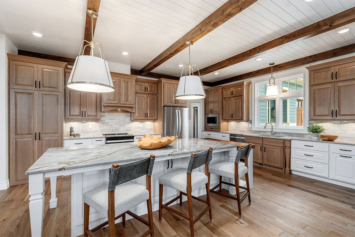 Brown-stained and white kitchen perimeter and island cabinets. Island includes decorative legs and seating.
