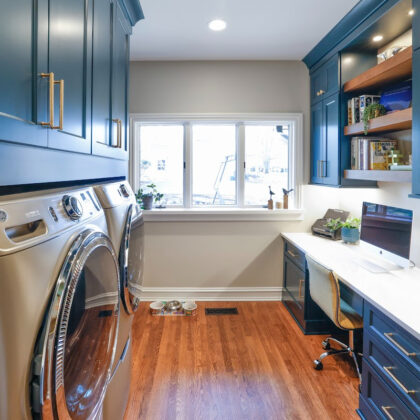 Emerald blue laundry and office space with dog crate cabinet.