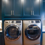 Emerald blue laundry cabinets with washer and dryer.