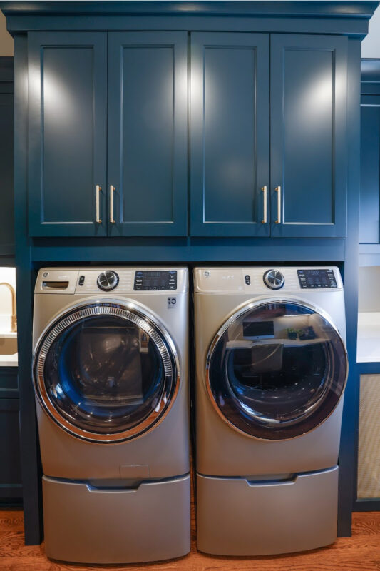 Emerald blue laundry cabinets with washer and dryer.