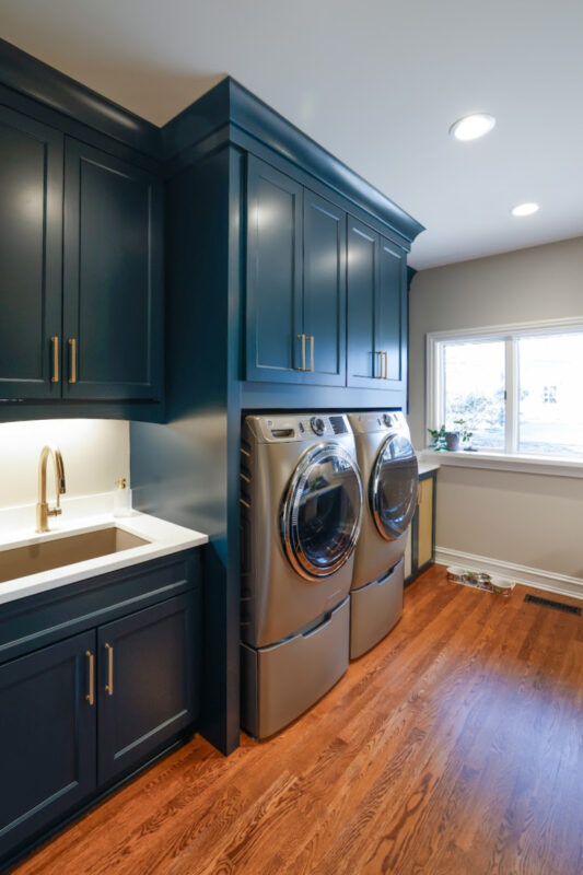 Emerald blue laundry and office space with dog crate cabinet.