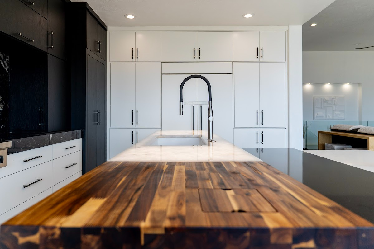 Modern white kitchen cabinets and a wood countertop near the sink in the island