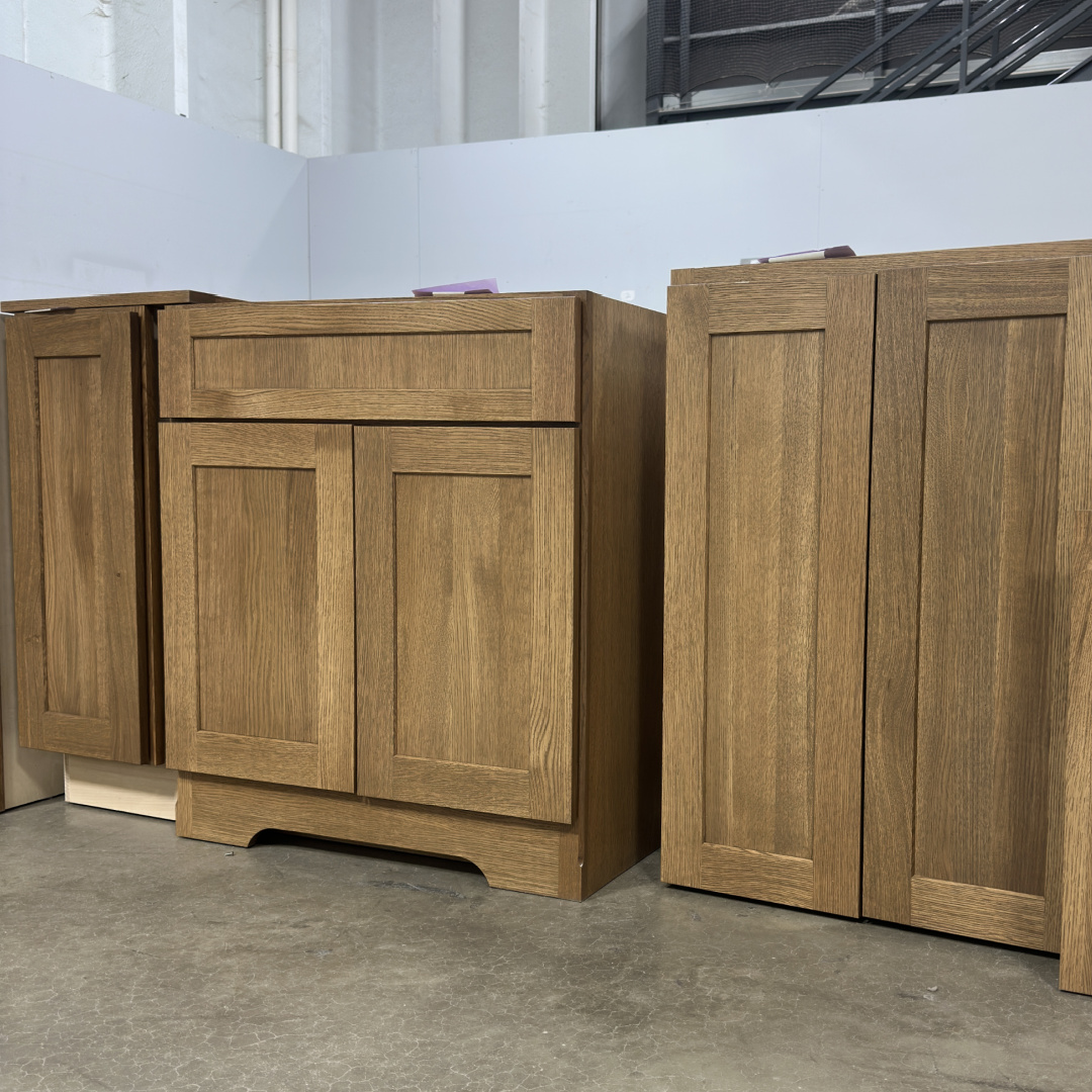 Base cabinet with arched toe and a wall cabinet in a warehouse setting. Finished with light brown Bourbon stain on rift white oak.