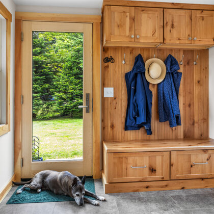 Rustic Alder mudroom locker and seating with drawers under the wood top. Dog is lying on a rug by the back door.