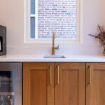 Cherry kitchen cabinets with a red Sienna stain. Small sink below a window is showing.