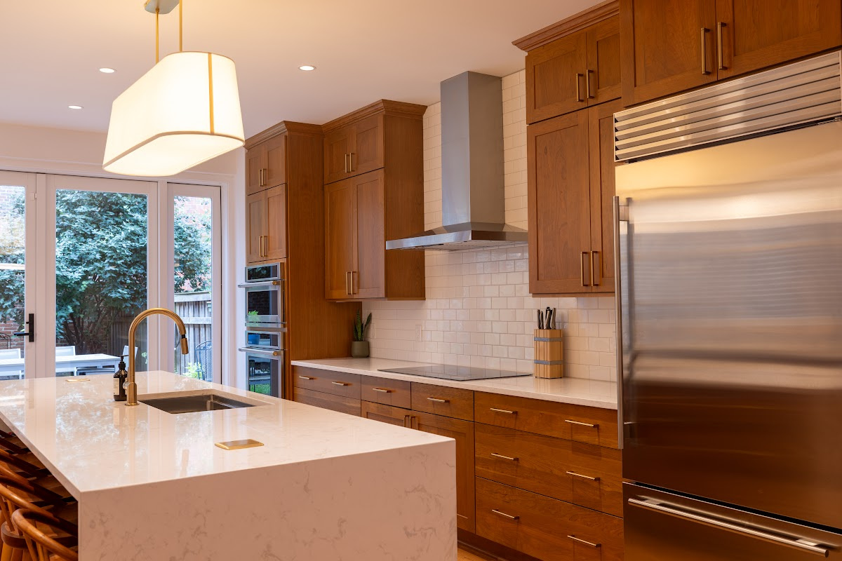 Cherry kitchen cabinets with a red Sienna stain. view shows stainless steel appliances on hood.