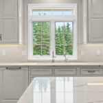 White kitchen perimeter cabinets in a view towards window above sink.