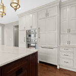 White kitchen perimeter cabinets with a dark cherry island.