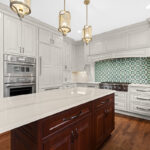 White kitchen perimeter cabinets with a dark cherry island.