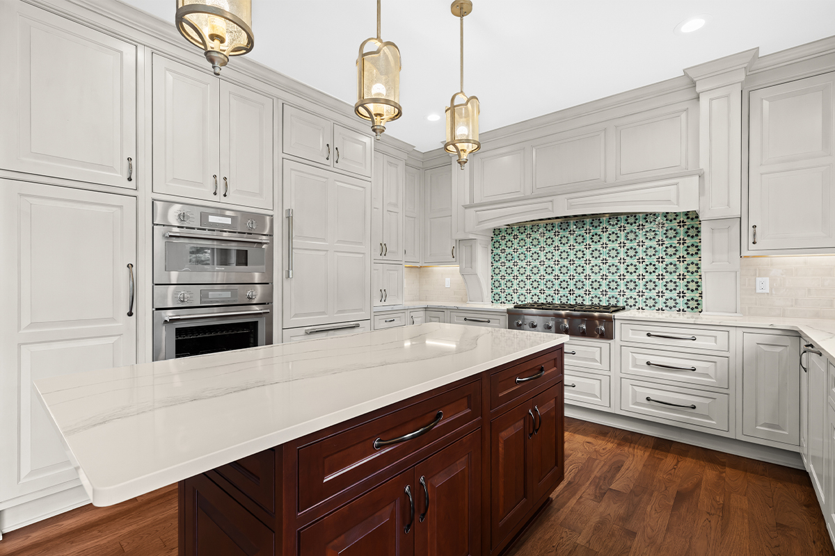 White kitchen perimeter cabinets with a dark cherry island.