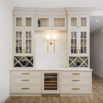 Gray painted bar cabinets with glass doors and criss-cross wine bottle racks.