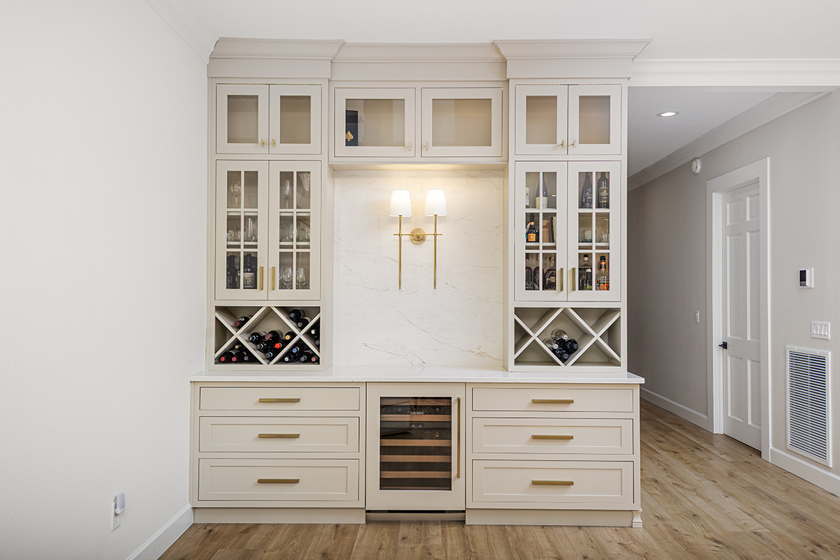 Gray painted bar cabinets with glass doors and criss-cross wine bottle racks.