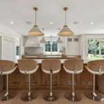 White and light brown kitchen cabinets. View is from the front of the island facing the hood and window.