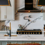 Painted Oyster primary kitchen cabinets with black appliances and green island.