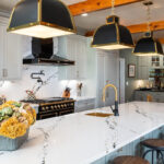 Painted Oyster primary kitchen cabinets with black appliances and green island.