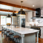 Painted Oyster primary kitchen cabinets with black appliances and green island.