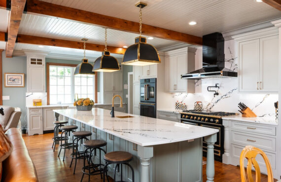 Painted Oyster primary kitchen cabinets with black appliances and green island.