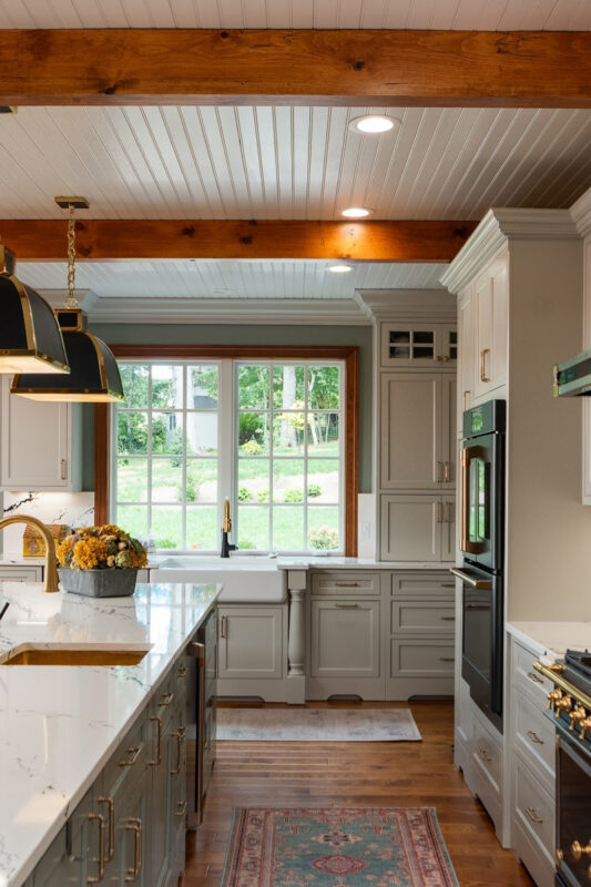 Painted Oyster primary kitchen cabinets with black appliances and green island.