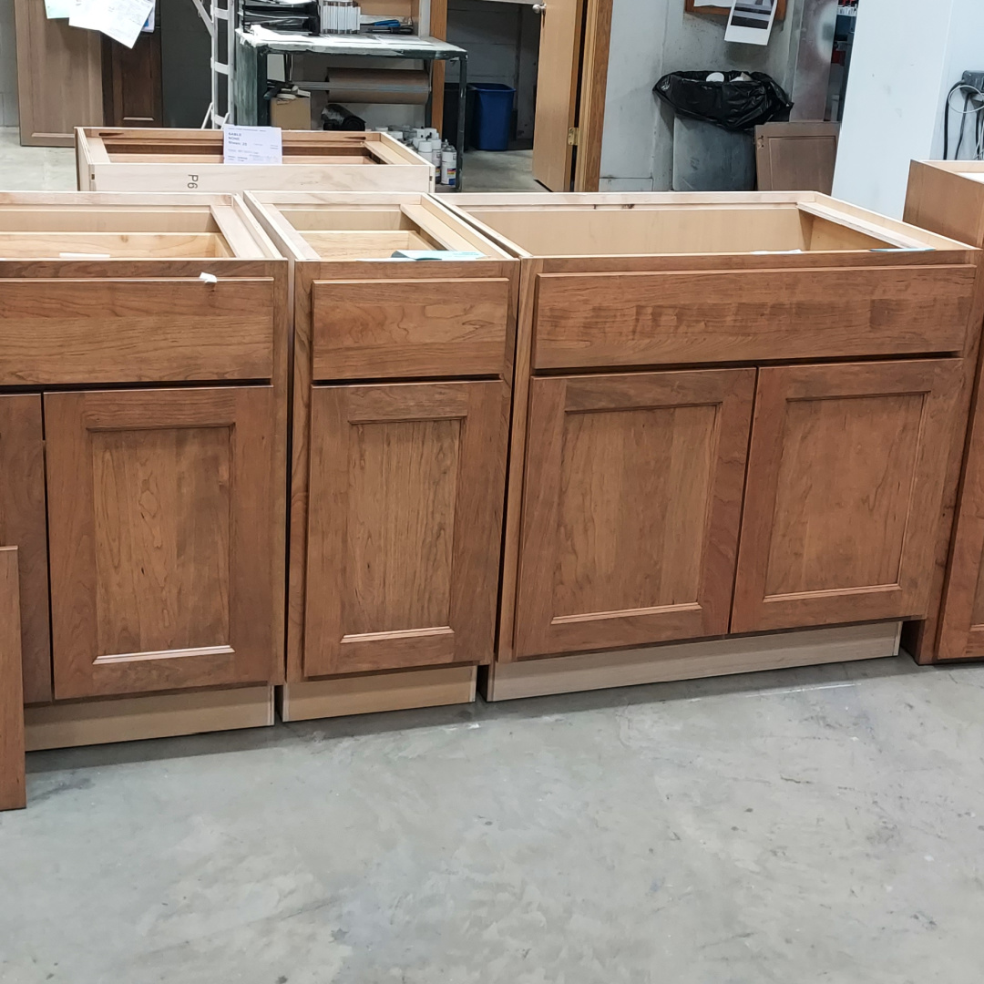 Base cabinets in a warehouse setting in cherry wood on Concord door style, finished in Bourbon stain.