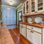 Hutch with natural wood cabinet frame and white doors and headers with blue tall storage cabinet with bench seating.