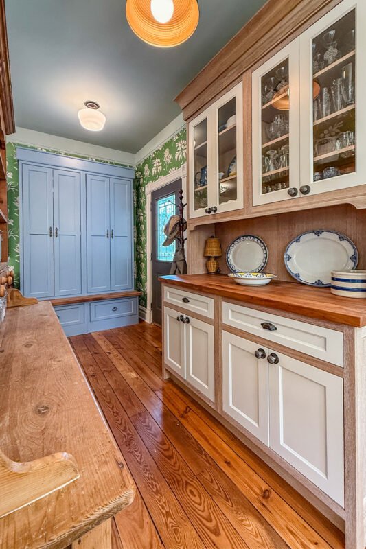 Hutch with natural wood cabinet frame and white doors and headers with blue tall storage cabinet with bench seating.