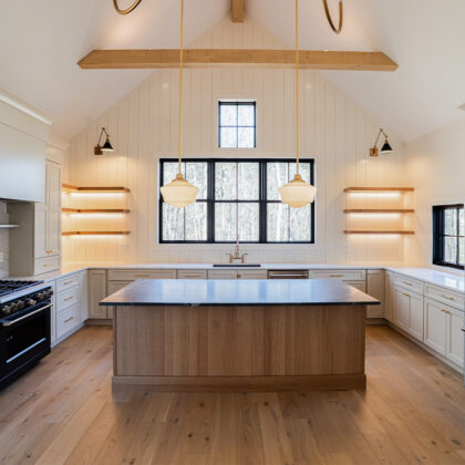 Light beige kitchen cabinets with hood and floating shelves. Also, visible is an island in rift white oak.