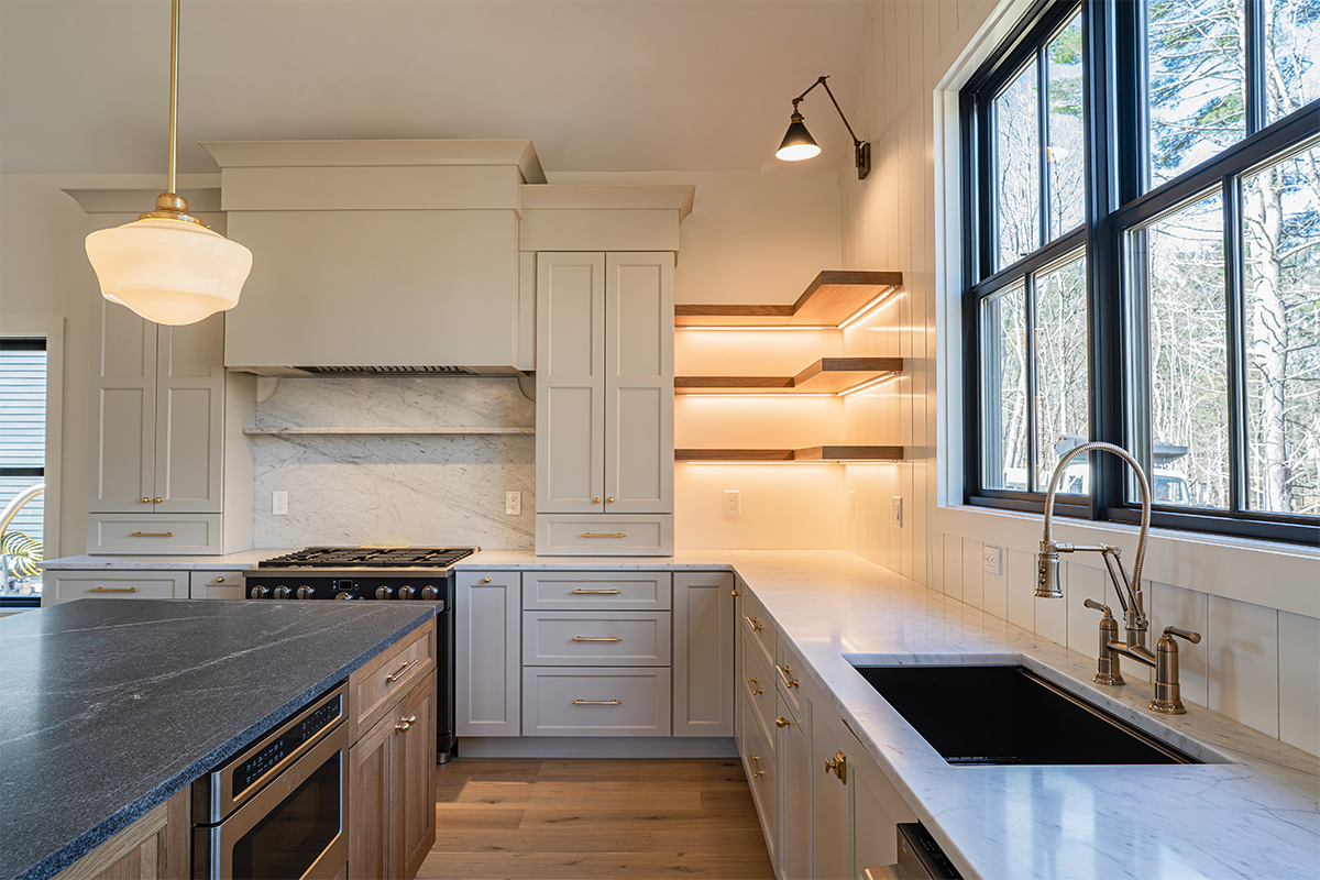 Light beige kitchen cabinets with hood and floating shelves.
