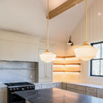 Light beige kitchen cabinets with hood and floating shelves.
