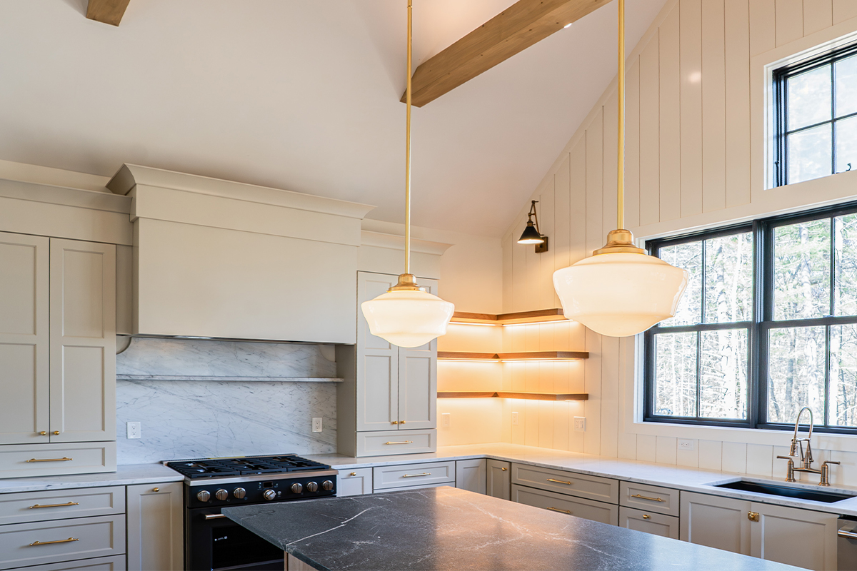 Light beige kitchen cabinets with hood and floating shelves.
